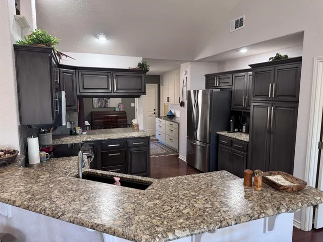 a kitchen with kitchen island granite countertop a refrigerator stove and sink