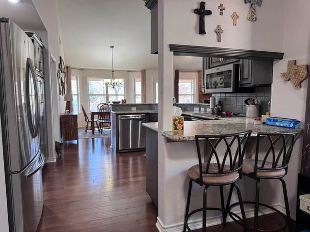 a kitchen with stainless steel appliances granite countertop a table chairs stove a refrigerator and cabinets