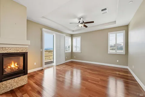 a view of an empty room with wooden floor fireplace and a window