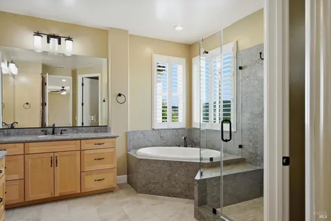 a bathroom with a granite countertop tub sink and mirror