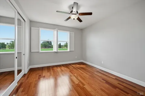a view of empty room with wooden floor and fan
