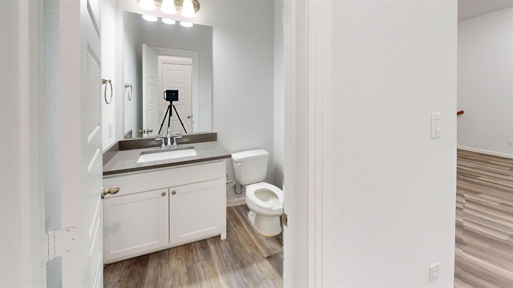 336 Buck Ridge Drive Frisco, TX 75068 - Photo 19 of 23 Bathroom featuring a single vanity with white cabinetry, a gray countertop, an integrated sink with a chrome faucet, and wood-finish flooring