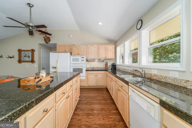 a kitchen with granite countertop white cabinets and white appliances