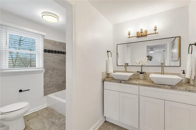 a bathroom with a granite countertop sink vanity mirror and toilet