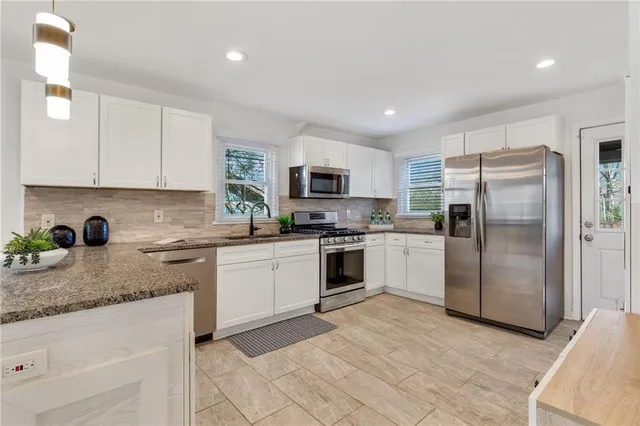 a kitchen with granite countertop a refrigerator sink and microwave