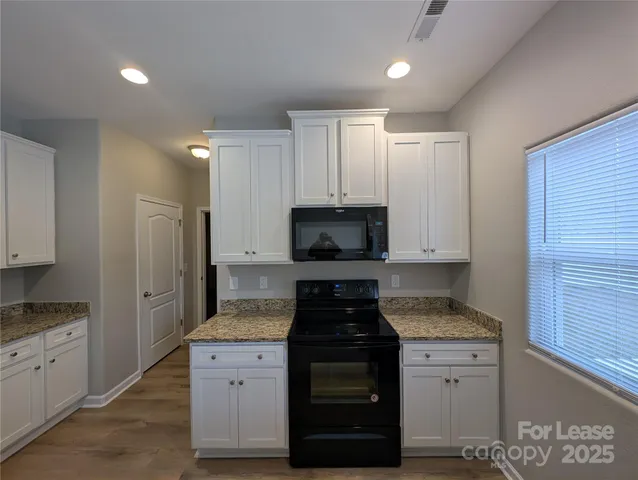 a kitchen with granite countertop white cabinets and stainless steel appliances