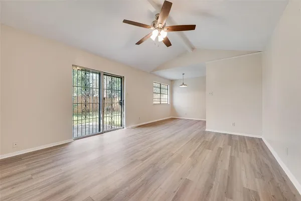 an empty room with wooden floor fan and windows