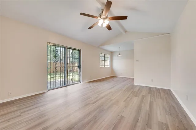 an empty room with wooden floor fan and windows