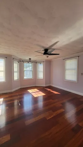 a view of empty room with wooden floor and fan