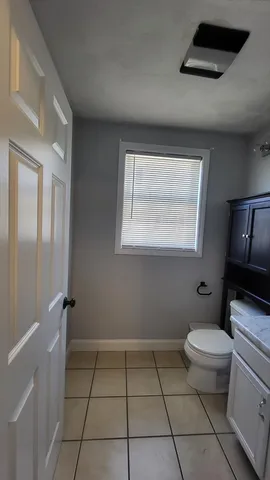 a bathroom with a granite countertop toilet a sink a mirror and a window