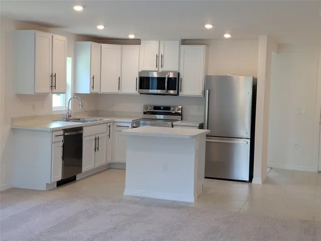 a kitchen with stainless steel appliances granite countertop white cabinets a refrigerator a sink and a stove