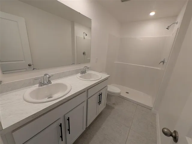 a bathroom with a double vanity sink and mirror with toilet