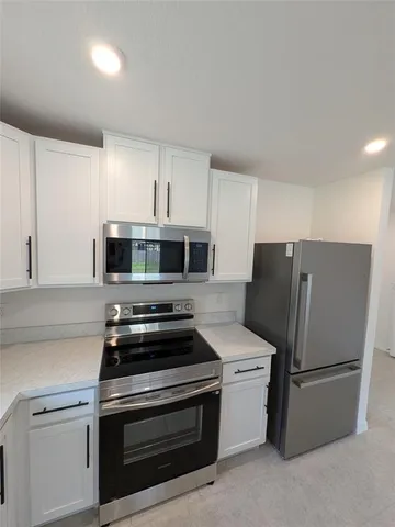 a kitchen with stainless steel appliances a refrigerator stove and white cabinets