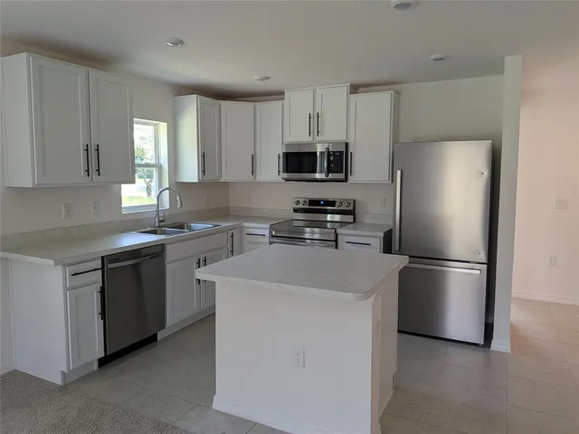 a kitchen with a refrigerator sink and cabinets