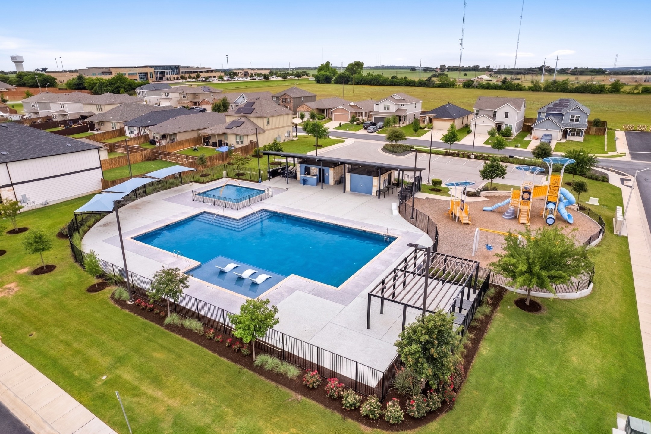 340 Harper Lane Georgetown, TX 78626 - Photo 27 of 28 Community amenity center featuring a large swimming pool with sun shelf, a separate wading pool, and a shaded playground area