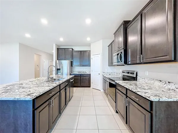 a large kitchen with stainless steel appliances granite countertop a granite counter tops a stove a sink and a refrigerator