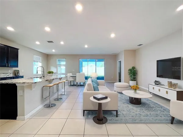 a living room with furniture a flat screen tv and kitchen view