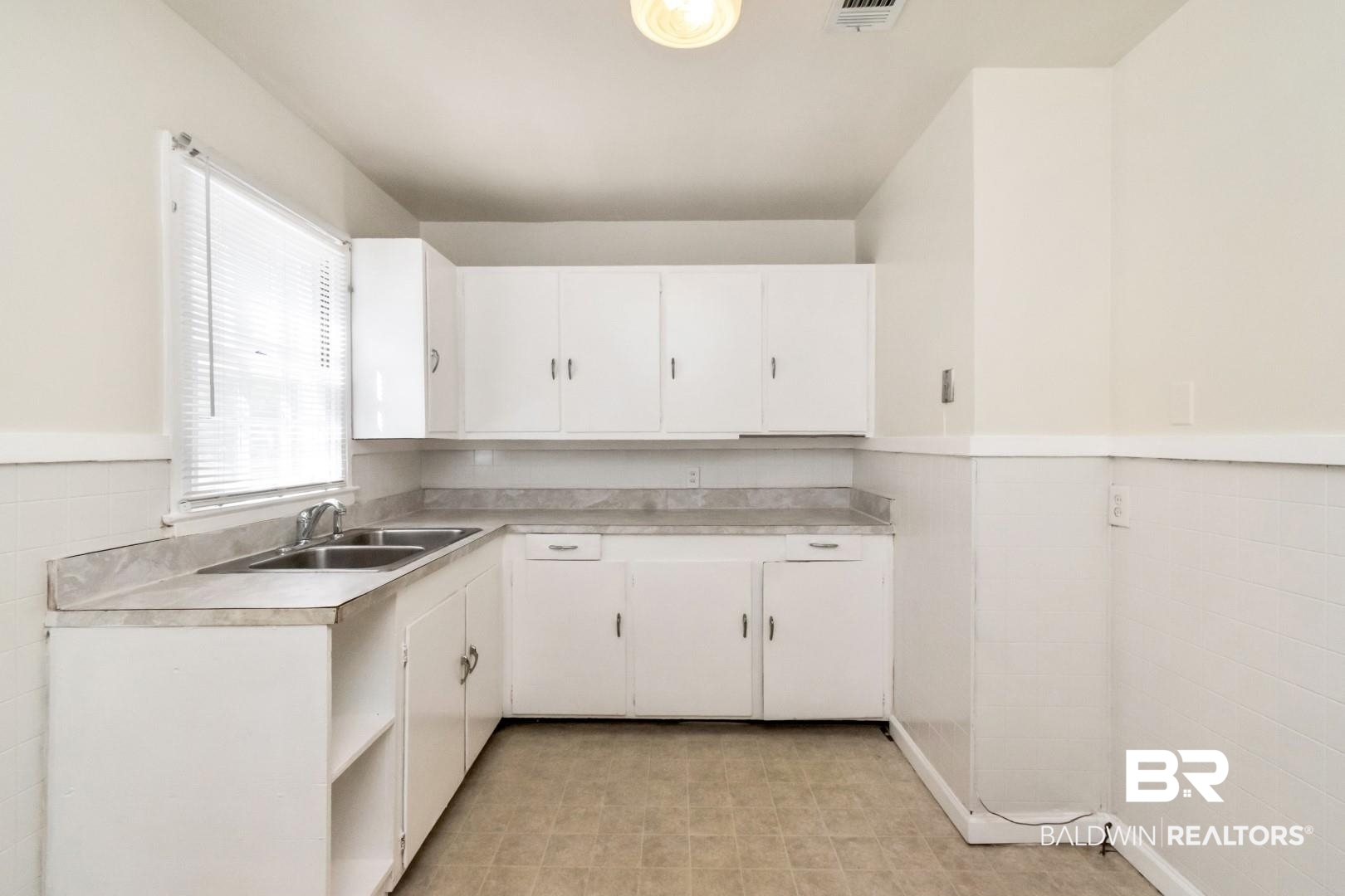 1477 Fairfield Street Mobile, AL 36606 - Photo 16 of 34 Kitchen featuring a wainscoted wall, white cabinets, light countertops, and light flooring