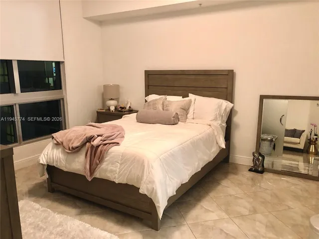 a large bed sitting in a bedroom next to a flat tv screen on wall