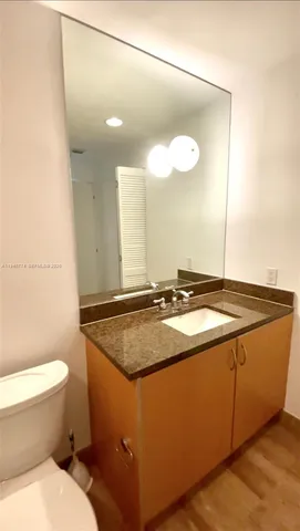 a bathroom with a granite countertop sink a toilet a mirror and vanity