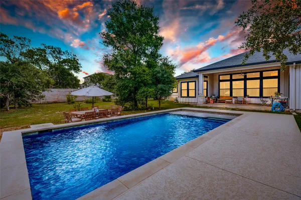 a view of swimming pool with lawn chairs and plants