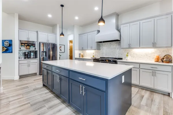 a kitchen with stainless steel appliances kitchen island a refrigerator sink and cabinets