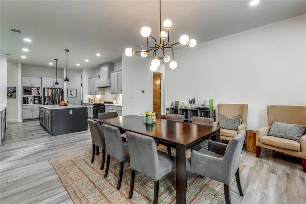 a dining room with wooden floor a chandelier a wooden table and chairs