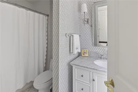a bathroom with a granite countertop sink toilet and mirror