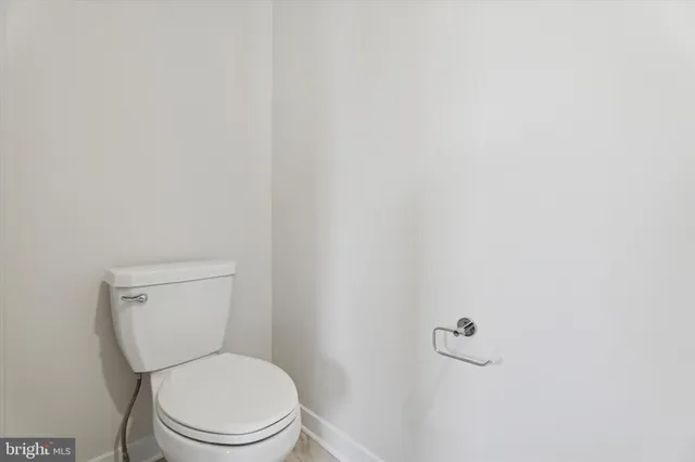a white toilet sitting next to a white wall