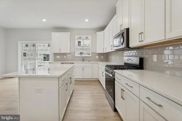 a kitchen with stainless steel appliances granite countertop a sink and dishwasher a stove top oven with white cabinets
