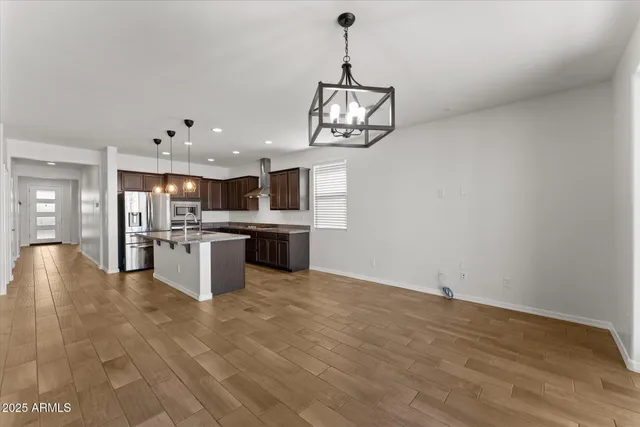 a view of a kitchen with kitchen island wooden floor and stainless steel appliances