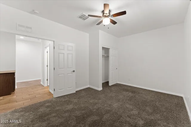 a view of an empty room with a ceiling fan and window