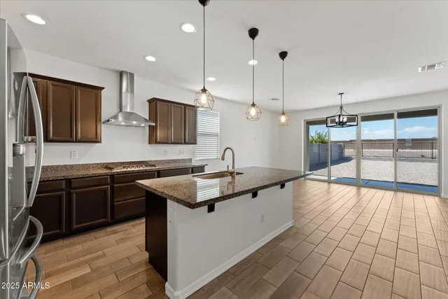 a kitchen with stainless steel appliances granite countertop a sink a stove and a wooden floors