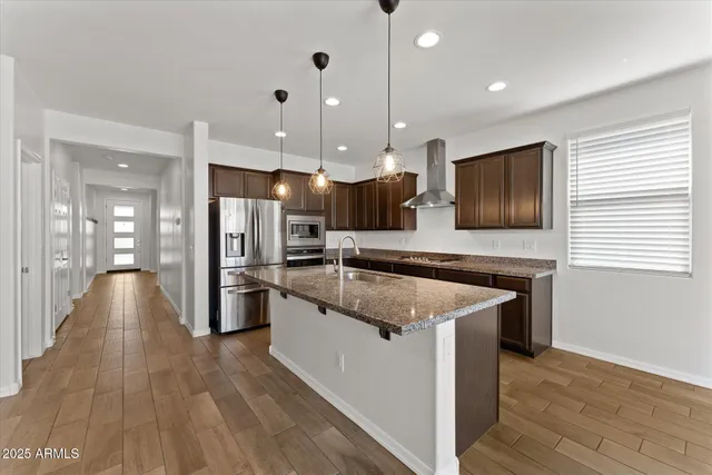 a kitchen with stainless steel appliances granite countertop a stove refrigerator and a sink