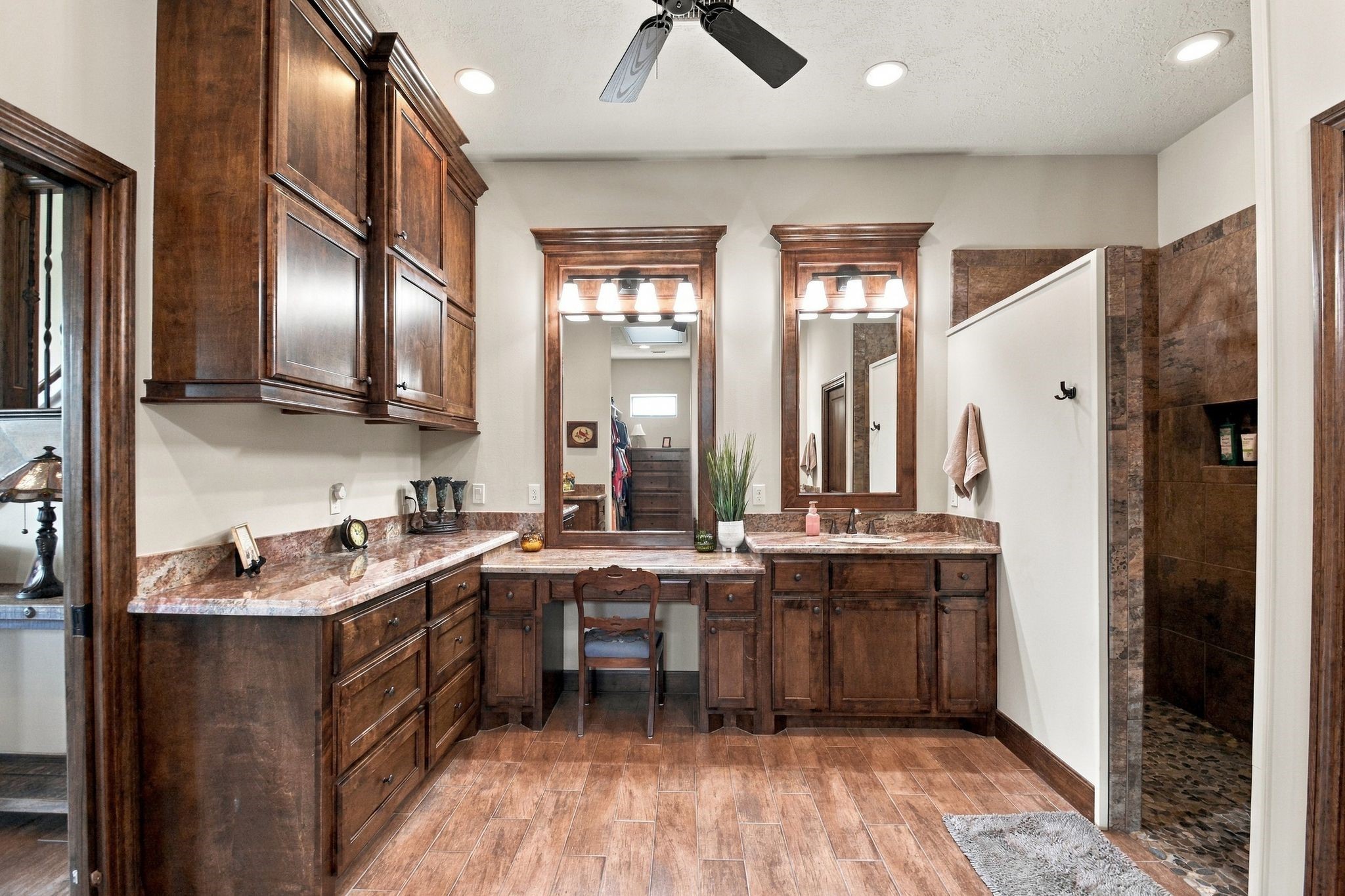 20341 Bay Hill Road Point Blank, TX 77364 - Photo 16 of 50 Elegant bathroom featuring rich wooden cabinetry, dual sinks with granite countertops, and a spacious walk-in shower, all complemented by warm, recessed lighting.