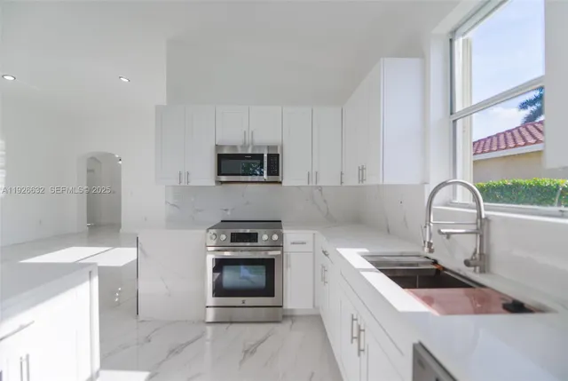 a bathroom with a granite countertop sink a vanity a window and a bathtub