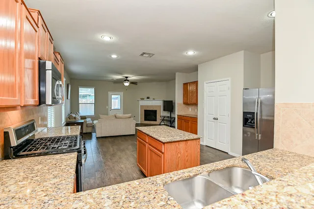 a kitchen with stainless steel appliances kitchen island granite countertop a refrigerator and a stove top oven