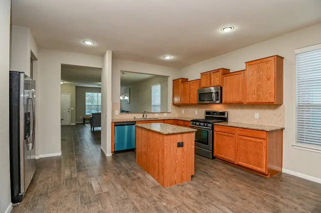 a large kitchen with stainless steel appliances granite countertop a stove and a sink