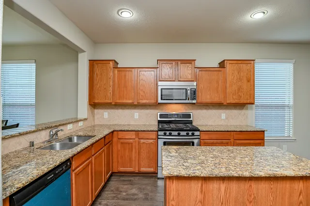 a kitchen with stainless steel appliances granite countertop a sink stove and cabinets