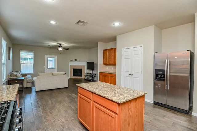 a kitchen with granite countertop a refrigerator a stove a sink dishwasher and wooden floor