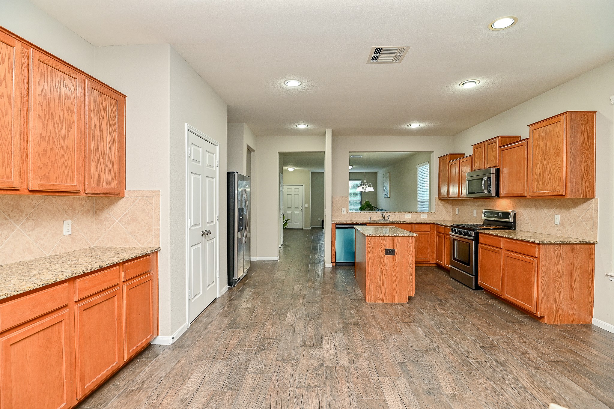 15406 Key Crest Lane Cypress, TX 77429 - Photo 25 of 47 a large kitchen with stainless steel appliances granite countertop a stove a sink dishwasher and a refrigerator with wooden floor
