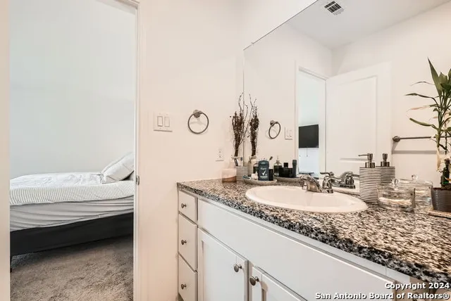 a bathroom with a granite countertop sink and a mirror