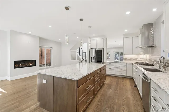 a large kitchen with a large counter top a sink stainless steel appliances and cabinets