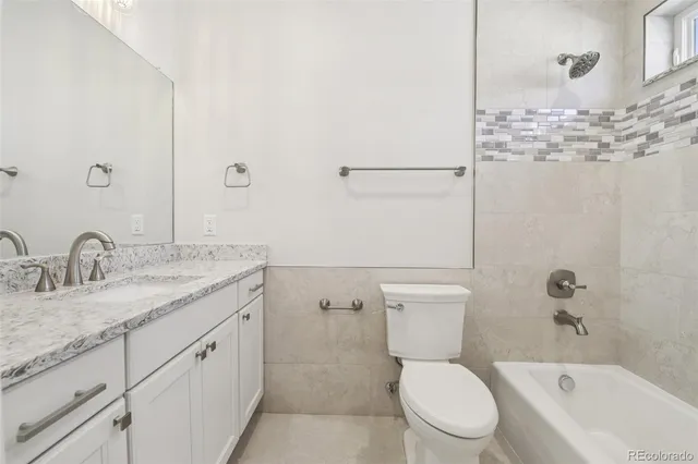 a bathroom with a granite countertop toilet a sink and a bathtub