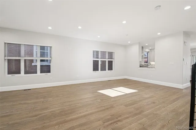 a view of an empty room with window and wooden floor