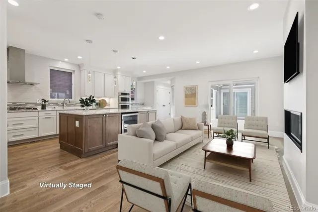 a living room with stainless steel appliances kitchen island granite countertop a couch and a flat screen tv
