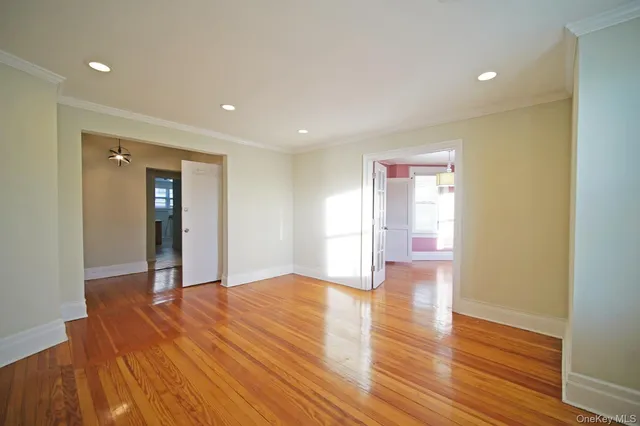 a view of an empty room with wooden floor and closet