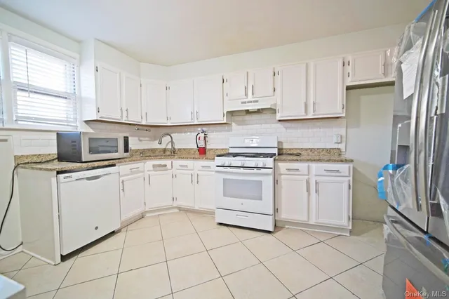 a kitchen with white cabinets appliances and a sink