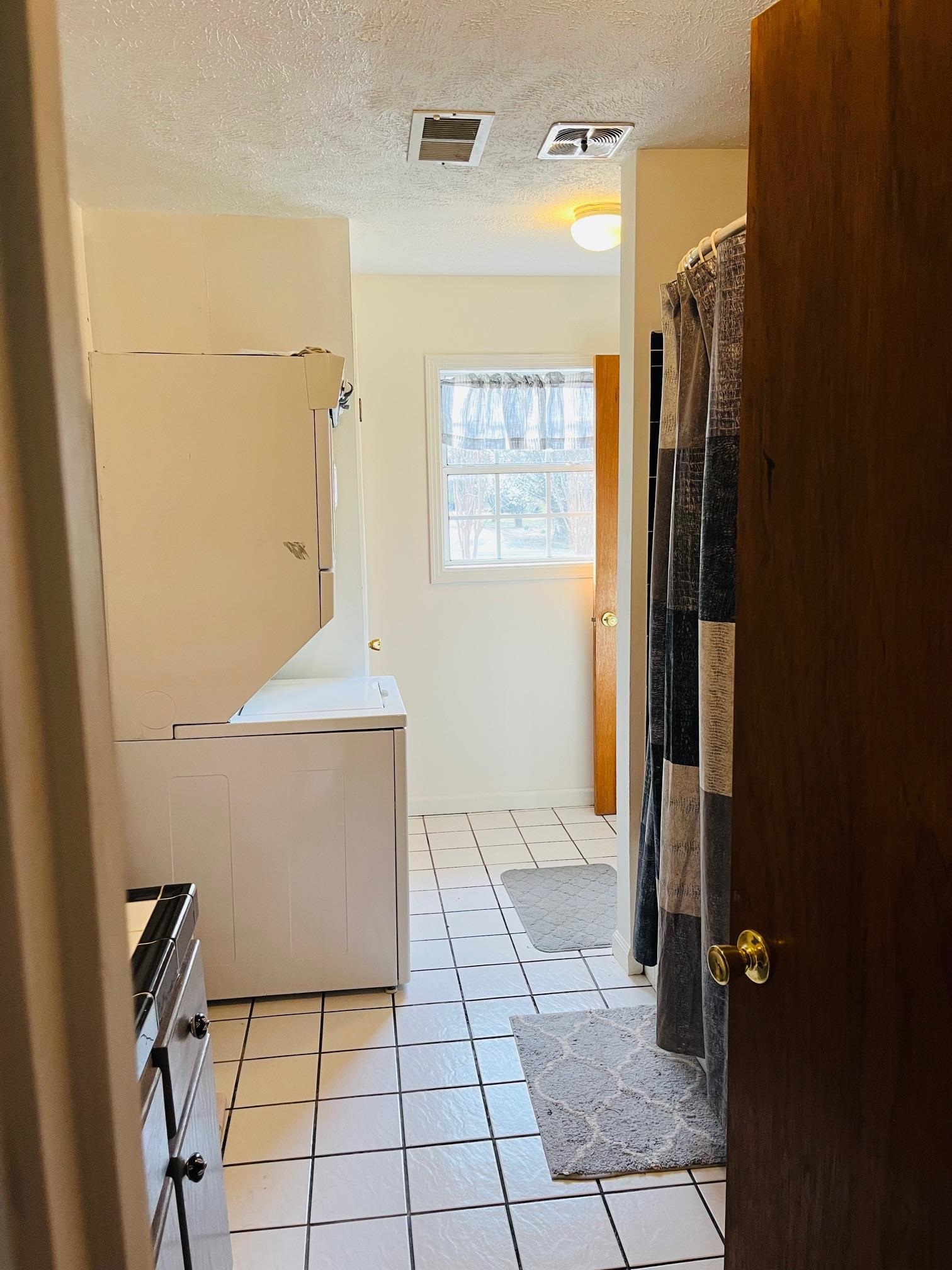 275 Fritton Spur Road Middleton, TN 38052 - Photo 8 of 31 Bathroom with vanity, curtained shower, a textured ceiling, light tile patterned floors, and washer / clothes dryer
