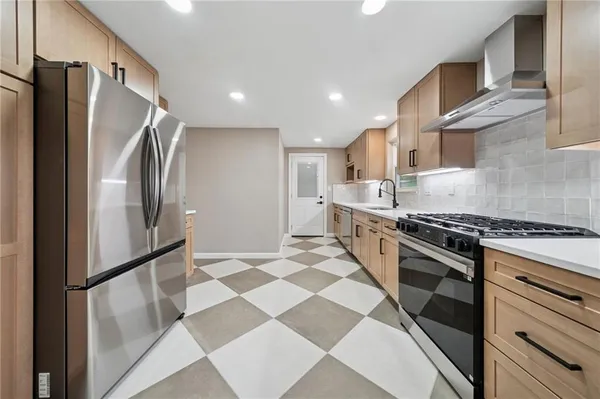 a kitchen with stainless steel appliances granite countertop a refrigerator and a stove top oven